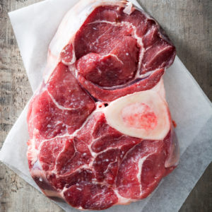 raw steak with bone in on butcher paper on table