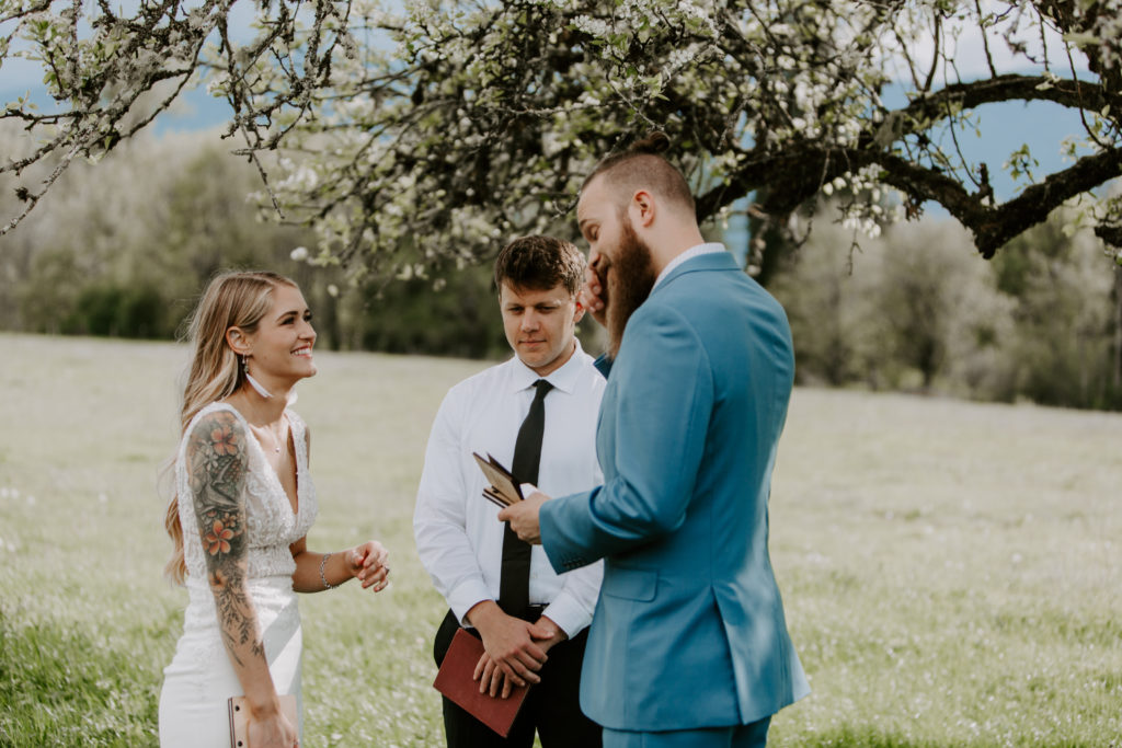 Modern couple in field beneath tree in a pasture saying vows